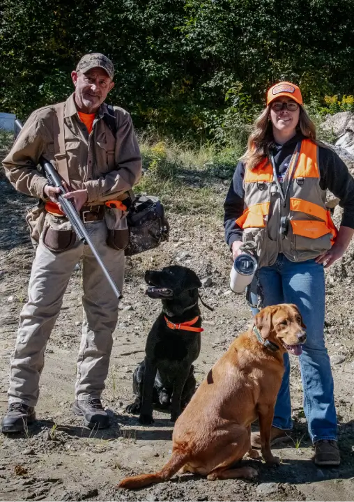 Hunters with shotguns and their dogs in outdoor setting at RiverVail Ranch, showcasing corporate hunting activities and training opportunities.