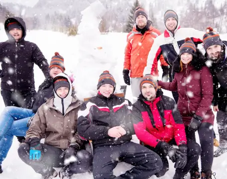 Group of people in winter clothing enjoying a snowy day at RiverVail Ranch, with snowman in the background, highlighting outdoor wellness and recreation activities.